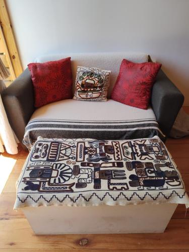 a couch with pillows and a blanket on it at Cabaña Jardín del Río in Junín de los Andes