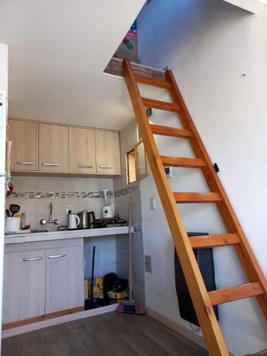 a kitchen with a wooden staircase in a room at Cabaña Jardín del Río in Junín de los Andes