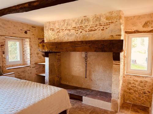 a bedroom with a bed and a stone fireplace at Le Moulin de Toquedonnes Gîte insolite in Saint-Michel