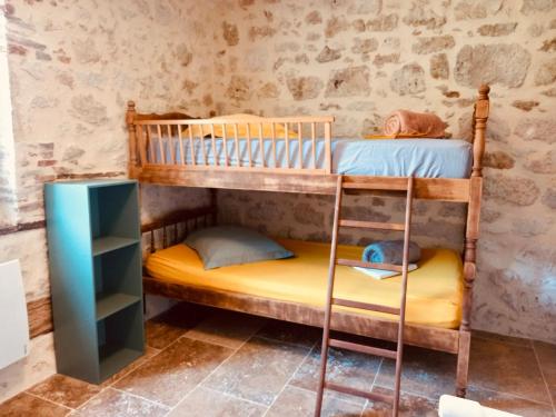 two bunk beds in a room with a stone wall at Le Moulin de Toquedonnes Gîte insolite in Saint-Michel
