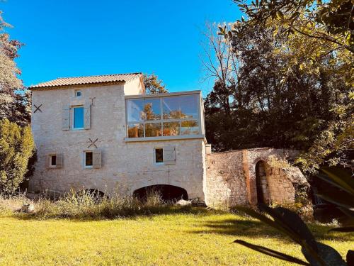 an old stone house with a large window on it at Le Moulin de Toquedonnes Gîte insolite in Saint-Michel