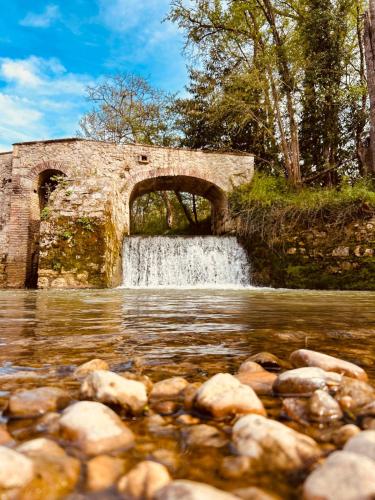a stone bridge over a river with a waterfall at Le Moulin de Toquedonnes Gîte insolite in Saint-Michel