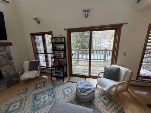 a living room with two chairs and a large window at VT Lake house minutes from Okemo in Ludlow