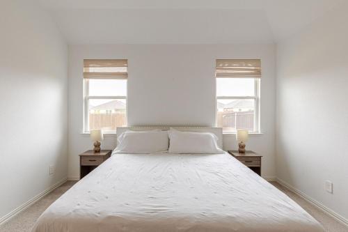 a white bedroom with a large bed with two windows at Southern Luxery Private Yard Tesla Plug BBQ Grill in Haslet