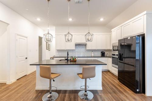 a kitchen with white cabinets and a island with two bar stools at Southern Luxery Private Yard Tesla Plug BBQ Grill in Haslet