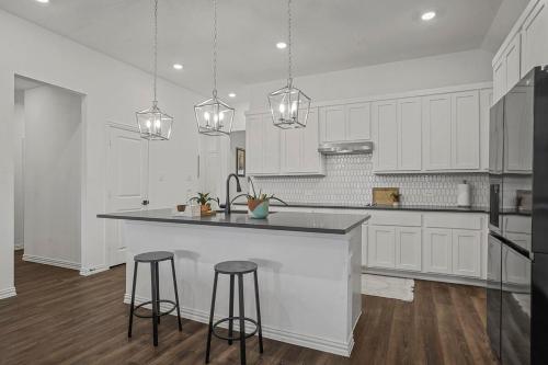 a kitchen with white cabinets and a counter and stools at Southern Luxery Private Yard Tesla Plug BBQ Grill in Haslet