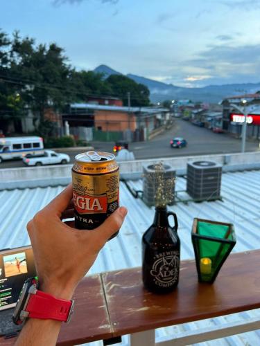 a person holding a can of cola next to a table at Hostal Sunset Town in Ahuachapán