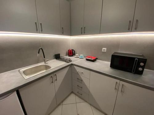 a kitchen with white cabinets and a sink and a microwave at Bridge Art Studio Chalkida in Chalkida