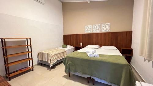 a bedroom with two beds with towels on them at Suítes Curió - Passarim Hospedagem in Cumuruxatiba