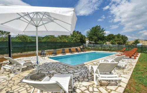 a pool with white chairs and an umbrella at Rooms Marija in Trilj