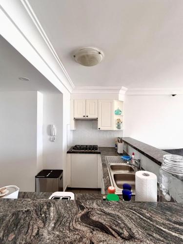 a kitchen with white cabinets and a granite counter top at 3BR Penthouse in CBD wParking in Sydney