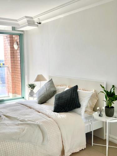 a white bedroom with a large bed and a window at 3BR Penthouse in CBD wParking in Sydney