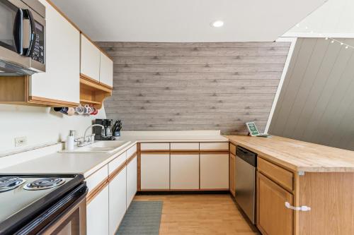 a kitchen with white cabinets and a wooden wall at Loch Nez, a spacious 3-bedroom home in Silver Lake, MI in Mears