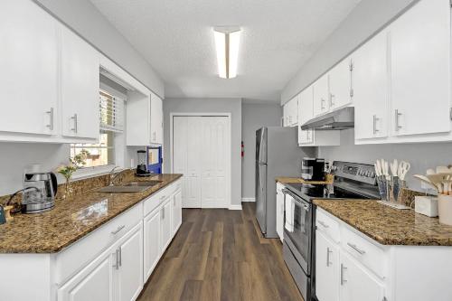 a kitchen with white cabinets and wooden floors at Cozy Villa with Spacious Outdoor Space in Orange City