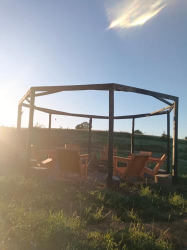 a group of chairs sitting under a gazebo in a field at casa rural el saltillo in Pemuco