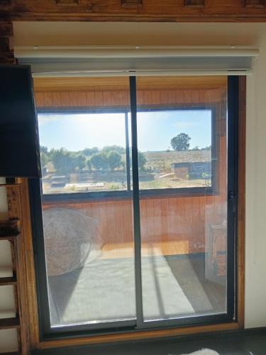 a window with a view of a field through it at casa rural el saltillo in Pemuco