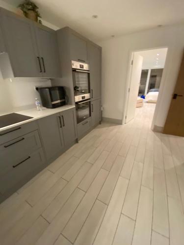a kitchen with white cabinets and a wooden floor at The bay apartment in Stone Grove