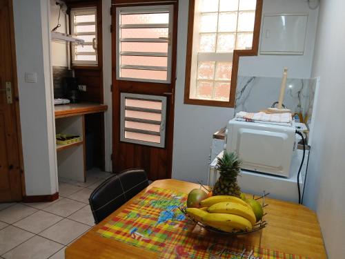 a table with a bowl of bananas and a pineapple on it at Smart-lidays in Sainte-Anne