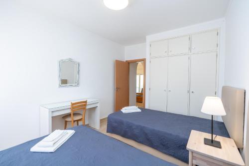 a bedroom with two beds and a desk and a table at Renovated Algarve Apartments with Pool in Armação de Pêra