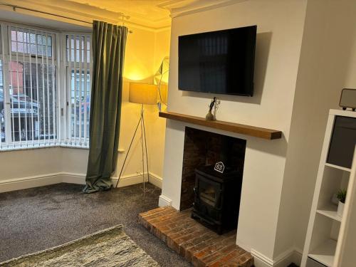 a living room with a fireplace with a flat screen tv at Cosy 2-bed NR New Cross Hospital in Wednesfield