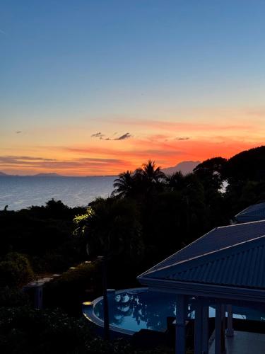 a view of a sunset from a resort with a swimming pool at Charmant T3 en haut de villa, vue panoramique sur la mer in Le Gosier