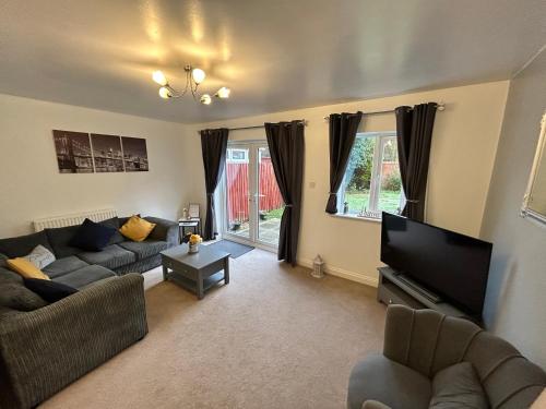 a living room with a couch and a flat screen tv at The Heathers - Spacious 3 Bed, Home from Home in Burton in Burton upon Trent