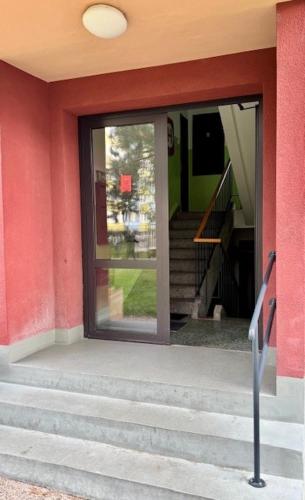 a red building with a glass door and stairs at Garsonka ve Dvoře in Dvůr Králové nad Labem