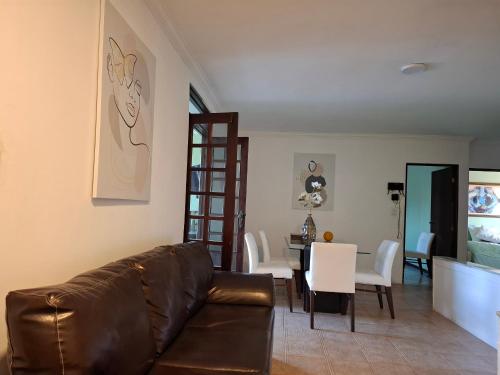 a living room with a couch and a dining room at Quarto Domiciliar em Antares Maceió in Maceió