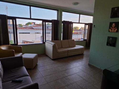 a living room with a couch and chairs and windows at Quarto Domiciliar em Antares Maceió in Maceió