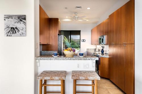 a kitchen with wooden cabinets and a counter with stools at J3 Kumulani in Hapuna Beach