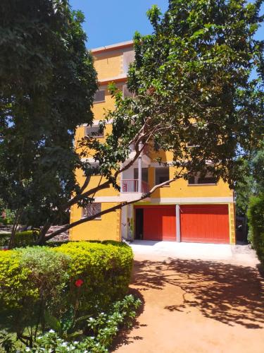 a yellow and red building with a red garage at Pearl Rangers Inn in Mbale