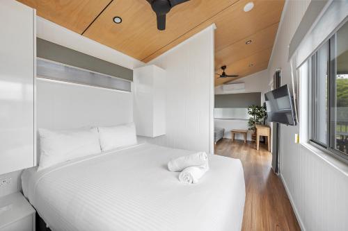 a bedroom with a large white bed and a window at Reflections Bermagui - Holiday Park in Bermagui