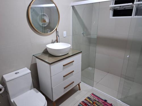 a white bathroom with a sink and a mirror at Quarto Domiciliar em Antares Maceió in Maceió