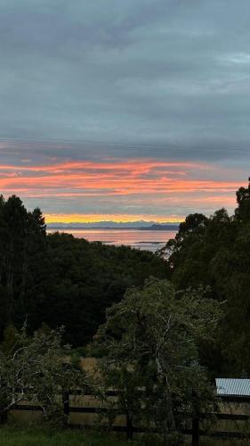 a sunset over the ocean with trees in the foreground at Refugio con Vista al Mar y Paz in Vilupulli