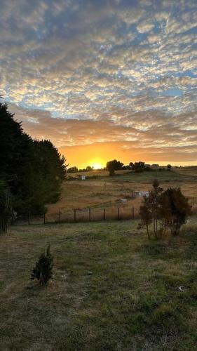 a sunset in a field with a fence at Refugio con Vista al Mar y Paz in Vilupulli