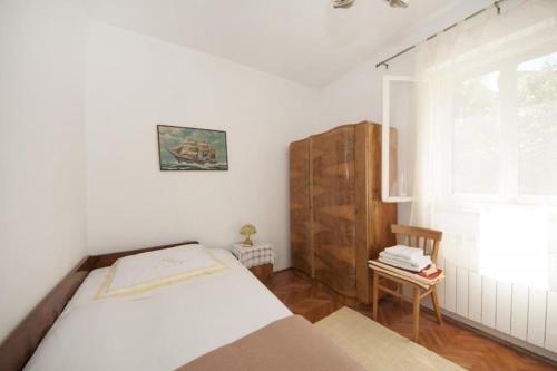 a white bedroom with a bed and a chair at Two Bedroom Apartment with Terrace A1 in Splitska