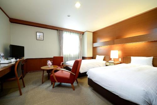 a hotel room with two beds and a desk at Daiichi Inn Park in Sendai