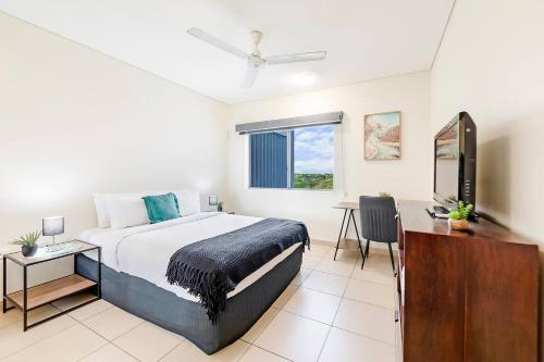 ein Schlafzimmer mit einem Bett, einem Schreibtisch und einem Fernseher in der Unterkunft Tropical Horizons - Chic Family Stay with Pool in Darwin