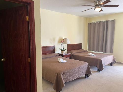 a hotel room with two beds and a ceiling fan at Hotel El Romano in Ixtapan de la Sal