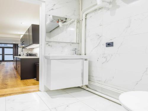 une cuisine blanche avec des murs en marbre blanc et un comptoir dans l'établissement Cosy apartment - 1BR 4P - Near Champs-Élysées, à Paris