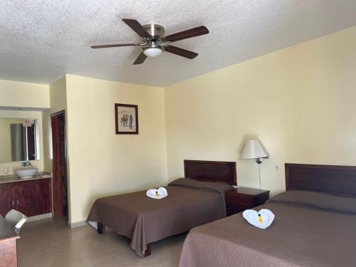 a bedroom with two beds and a ceiling fan at Hotel El Romano in Ixtapan de la Sal