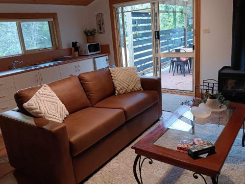 a living room with a brown couch and a table at The Olive House Tasmania in Flowerdale