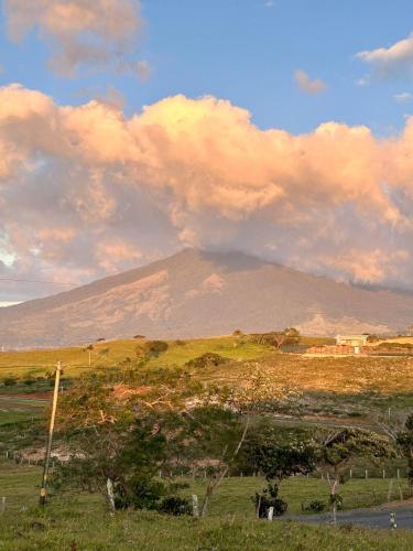 a field with a mountain in the background with clouds at Casa LORA Eco tourism or remote work in Bagaces