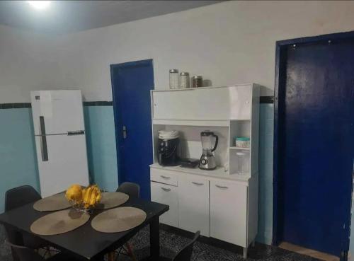 a small kitchen with a table and a refrigerator at Casa Praia Grande in Arraial do Cabo