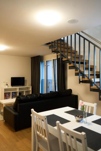 a living room with a black couch and a staircase at Duplex Apartment Bülach Station in Bülach
