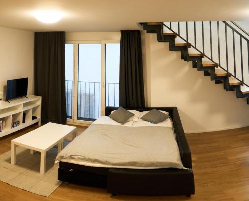a bedroom with a bed and a staircase at Duplex Apartment Bülach Station in Bülach