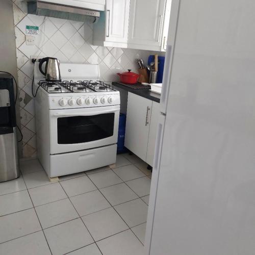 a kitchen with a white stove and white cabinets at Selens Apartment in Ti Rocher Micoud Saint Lucia in La Cour Ville