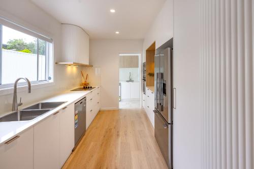 a kitchen with white cabinets and a wooden floor at Olas Villa 1 - Plunge Pool & Walk to Beach in Anna Bay