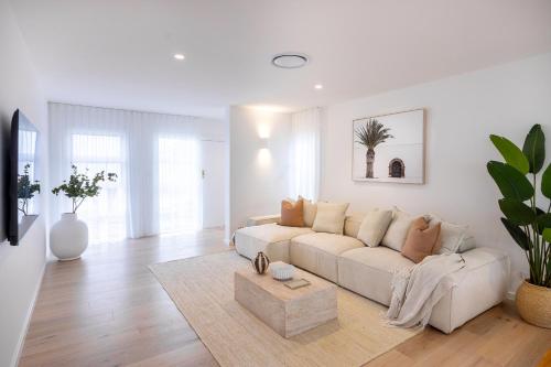 a white living room with a couch and a table at Olas Villa 1 - Plunge Pool & Walk to Beach in Anna Bay