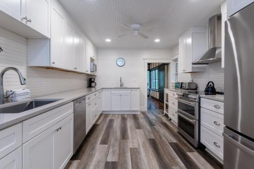 a kitchen with white cabinets and wooden floors at Pavillion Paradise is Walking Distance to Lake Michigan in Holland